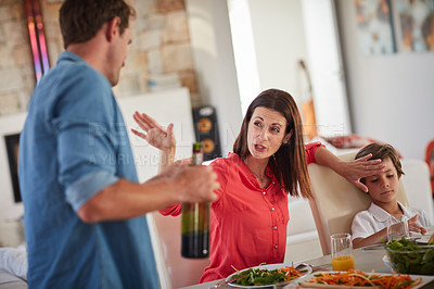 Buy stock photo Shot of a drunk man and his wife arguing in front of their children during lunch