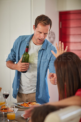 Buy stock photo Shot of a drunk man and his wife arguing in front of their children during lunch