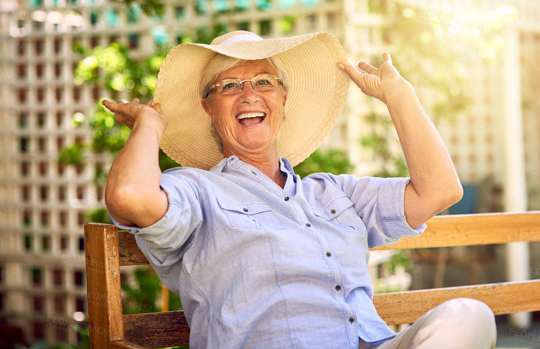 Buy stock photo Portrait, laugh and senior woman with hat on bench, relaxation and glasses in garden. Joke, seat and elderly female person in backyard for happiness, comedy and funny with retirement in Canada