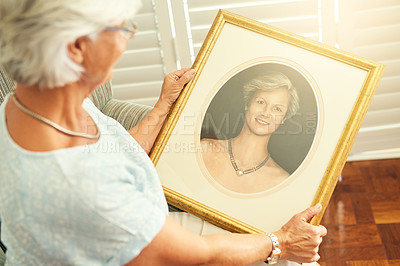 Buy stock photo High angle shot of a senior woman looking at a portrait of herself at home