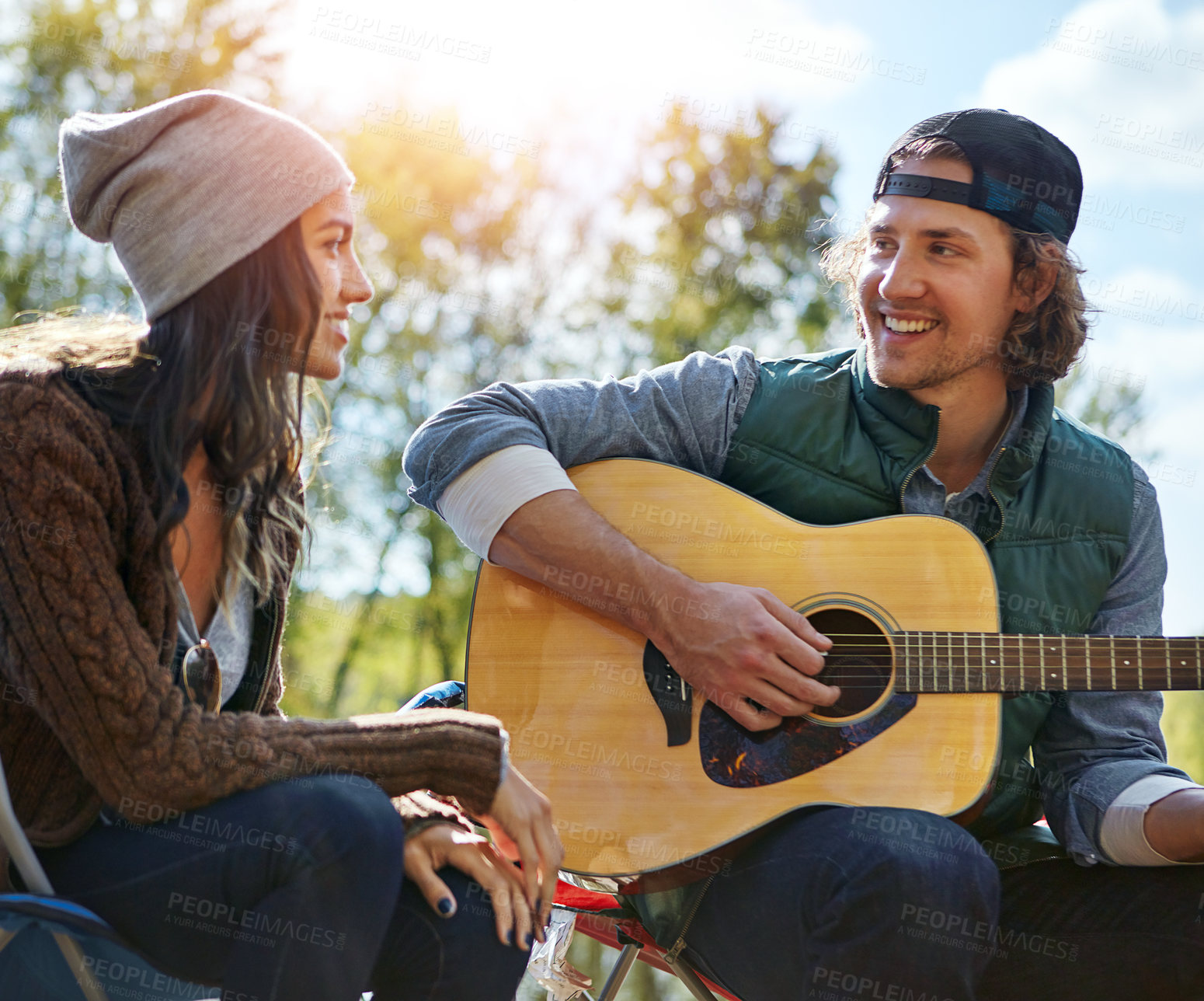 Buy stock photo Shot of a young man playing his girlfriend a song on his guitar