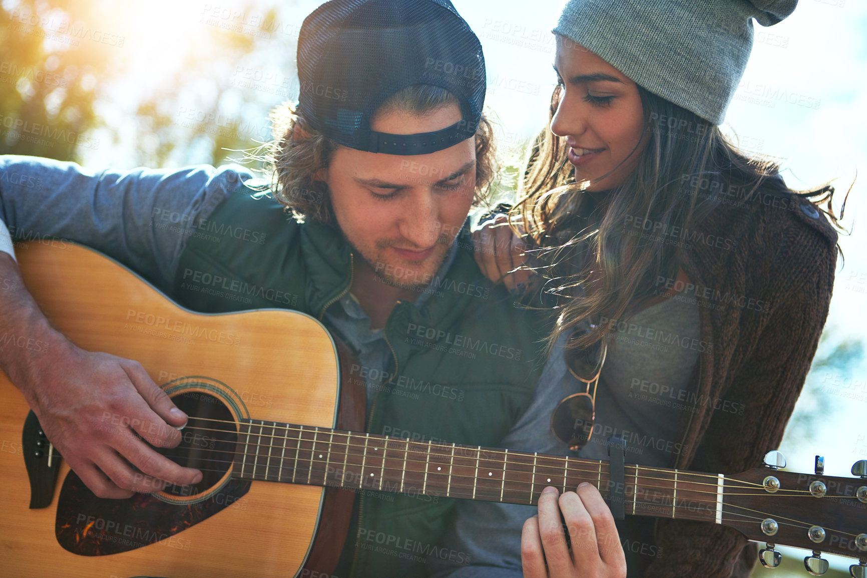 Buy stock photo Shot of a young man playing his girlfriend a song on his guitar