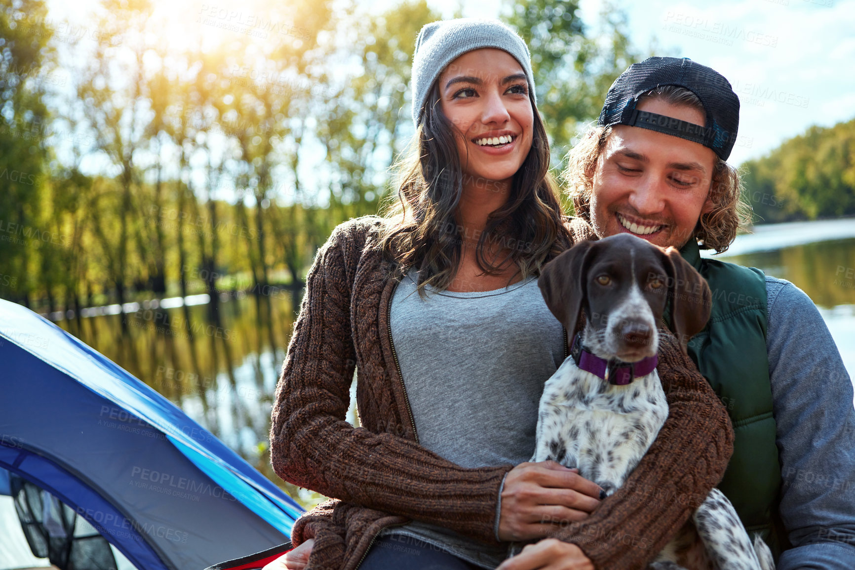 Buy stock photo Couple, camping and smile at lake with dog for freedom, adventure travel with sustainability. Man, woman and pet puppy in nature by water for relax on vacation, happiness and holiday environment