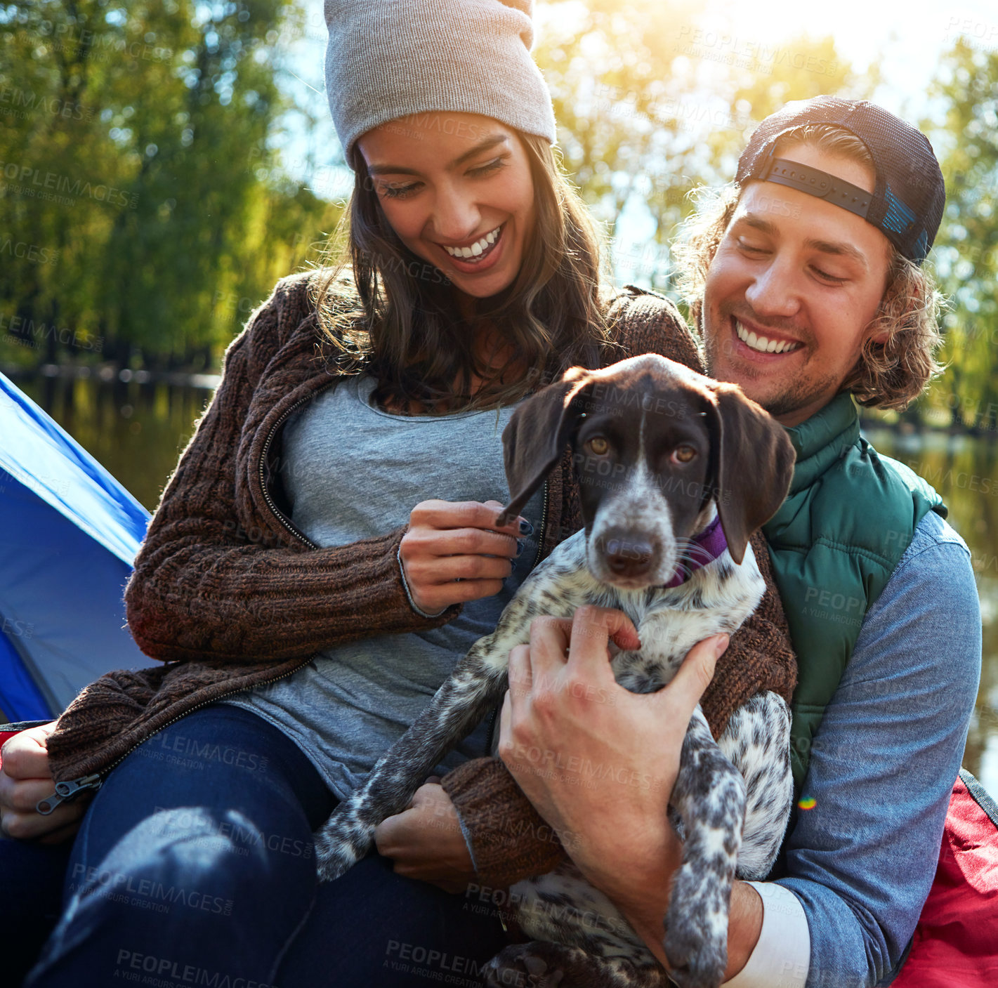 Buy stock photo Love, couple and dog in nature for camping in forest, sunshine and bonding, smile and support of animal on adventure time. Calm, woman and man with puppy pet for care, hug or relax in summer journey
