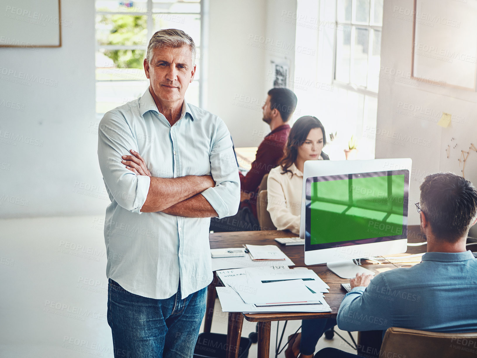 Buy stock photo Portrait of a mature man in the office with his colleagues working at their desks