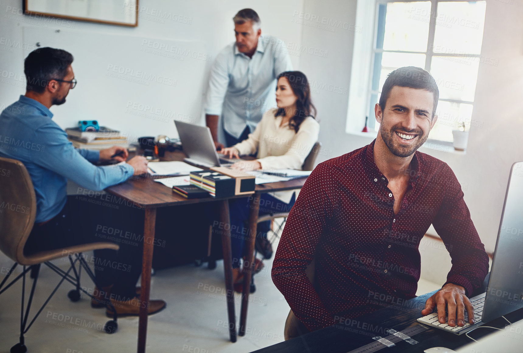 Buy stock photo Portrait of a young man working in the office with his colleagues in the background