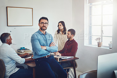 Buy stock photo Portrait of a mature man sitting on a desk in the office which his colleagues are working on
