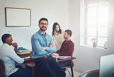 Buy stock photo Portrait of a mature man sitting on a desk in the office which his colleagues are working on