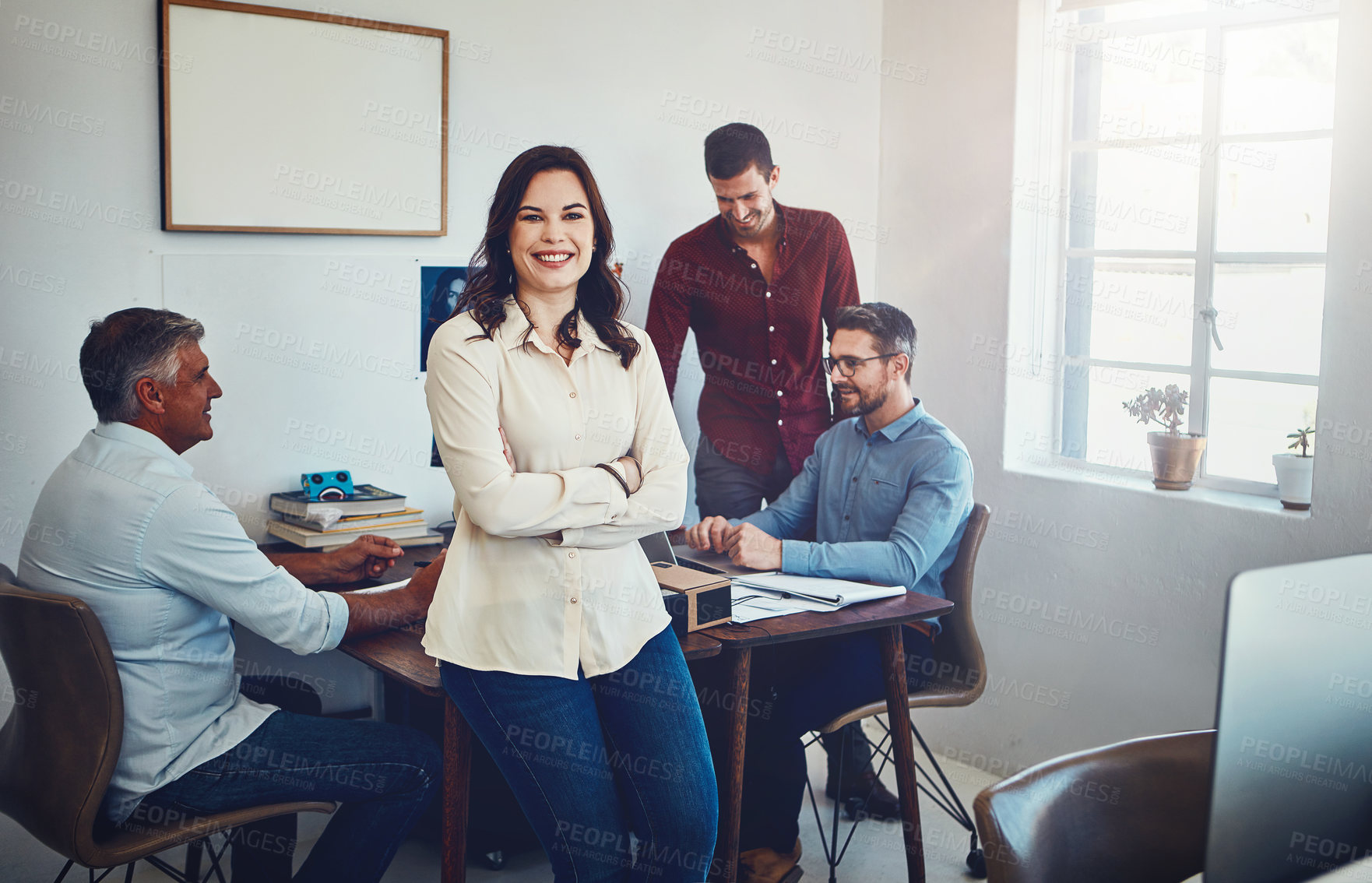 Buy stock photo Portrait of a young woman sitting on an office desk which her colleagues are working on