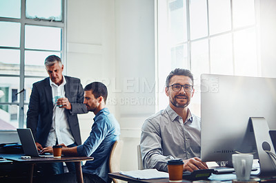 Buy stock photo Computer, portrait and businessman with his colleagues speaking in the background in the office. Technology, success and professional male employee working on a corporate project on a pc in workplace
