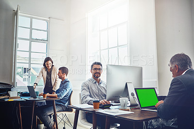 Buy stock photo Portrait of mature businessman using a computer at work with his colleagues in the background