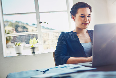 Buy stock photo Shot of a young businesswoman using a laptop at her work desk