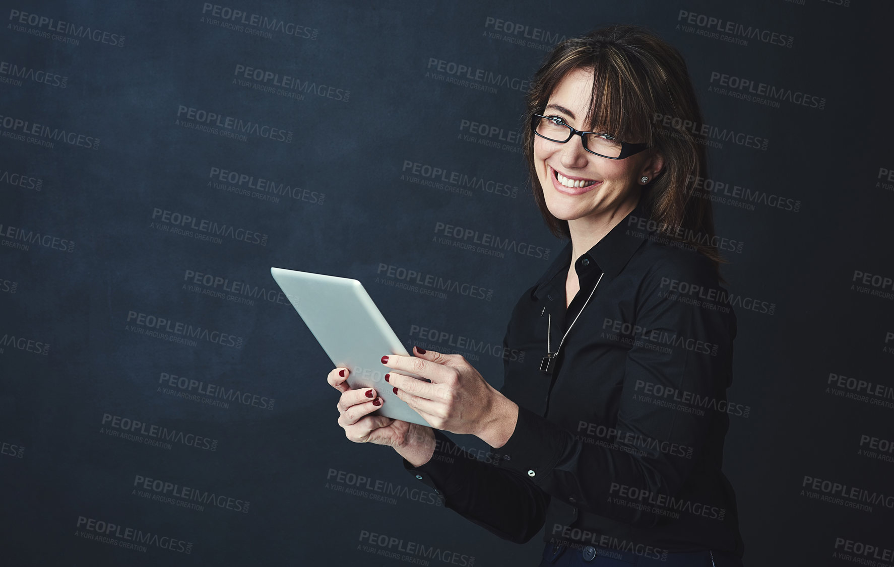 Buy stock photo Studio portrait of a corporate businesswoman using a digital tablet against a dark background