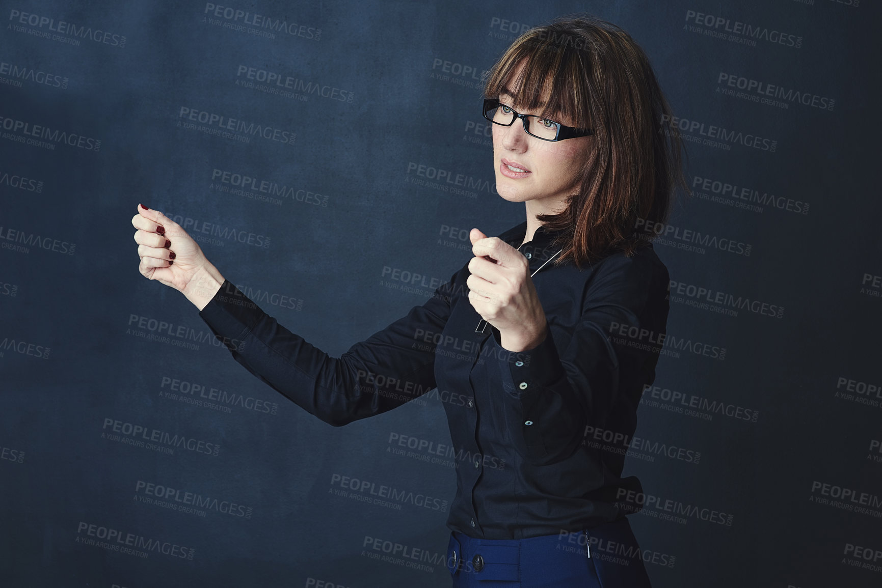 Buy stock photo Studio shot of a corporate businesswoman pretending to hold something against a dark background