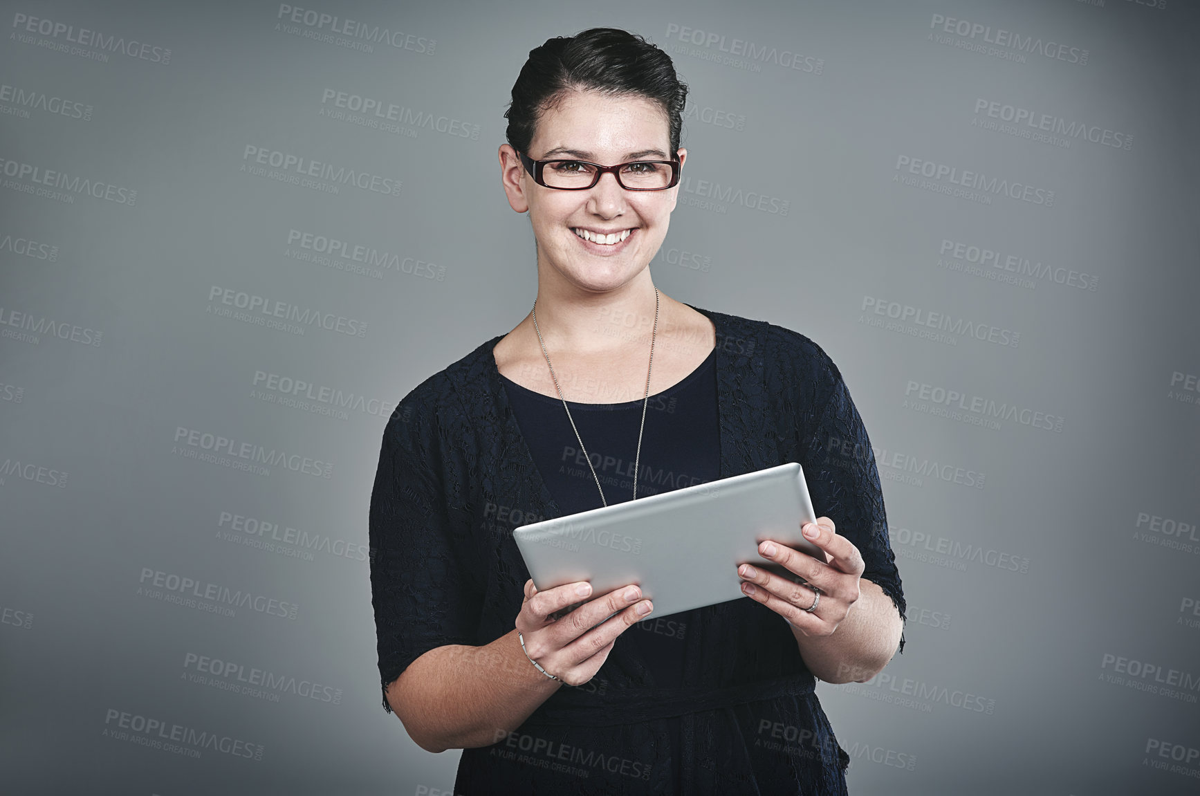 Buy stock photo Studio portrait of a young businesswoman using a digital tablet against a grey background