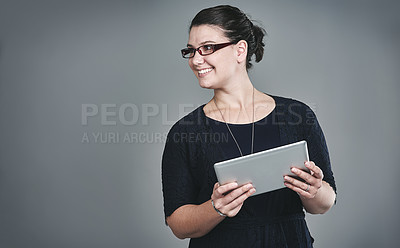 Buy stock photo Studio shot of a young businesswoman using a digital tablet against a grey background