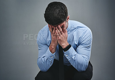 Buy stock photo Studio shot of a young businessman with his hands covering his face against a grey background