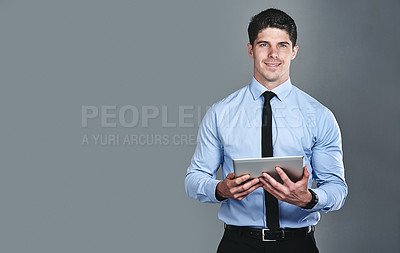 Buy stock photo Studio portrait of a young businessman using a digital tablet against a grey background