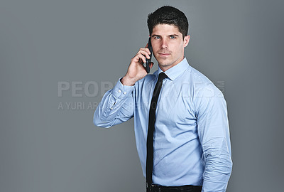 Buy stock photo Studio shot of a young businessman talking on a cellphone against a grey background