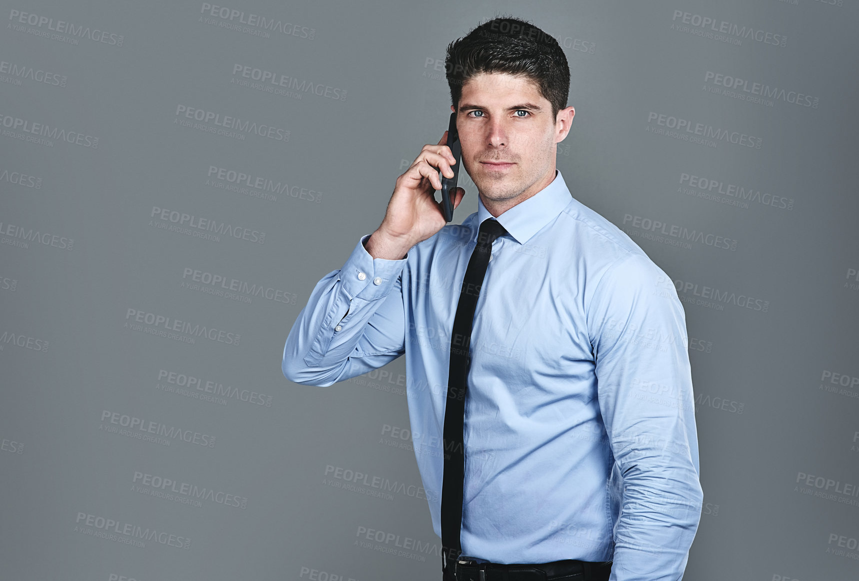 Buy stock photo Studio shot of a young businessman talking on a cellphone against a grey background