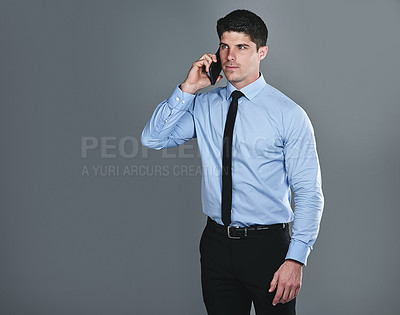 Buy stock photo Studio shot of a young businessman talking on a cellphone against a grey background