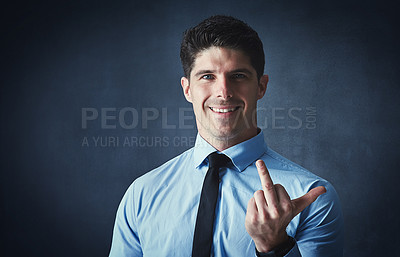 Buy stock photo Studio portrait of a young businessman showing the middle finger against a dark background