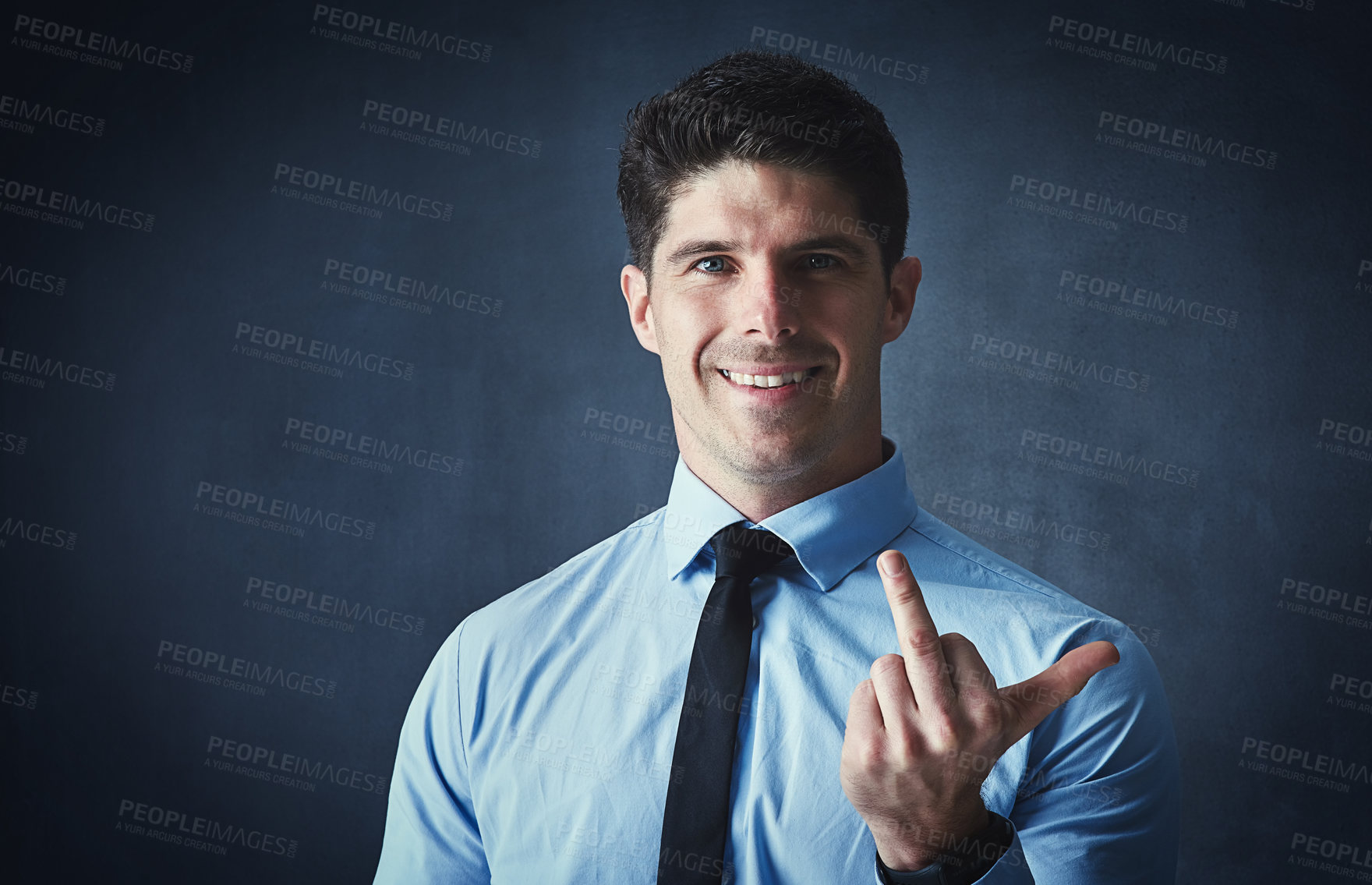 Buy stock photo Studio portrait of a young businessman showing the middle finger against a dark background