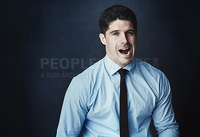 Buy stock photo Studio portrait of a young businessman making a face against a dark background