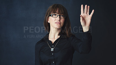 Buy stock photo Studio shot of a businesswoman connecting to a user interface with her finger against a dark background