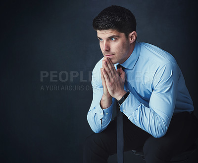 Buy stock photo Studio shot of a young businessman looking thoughtful against a dark background