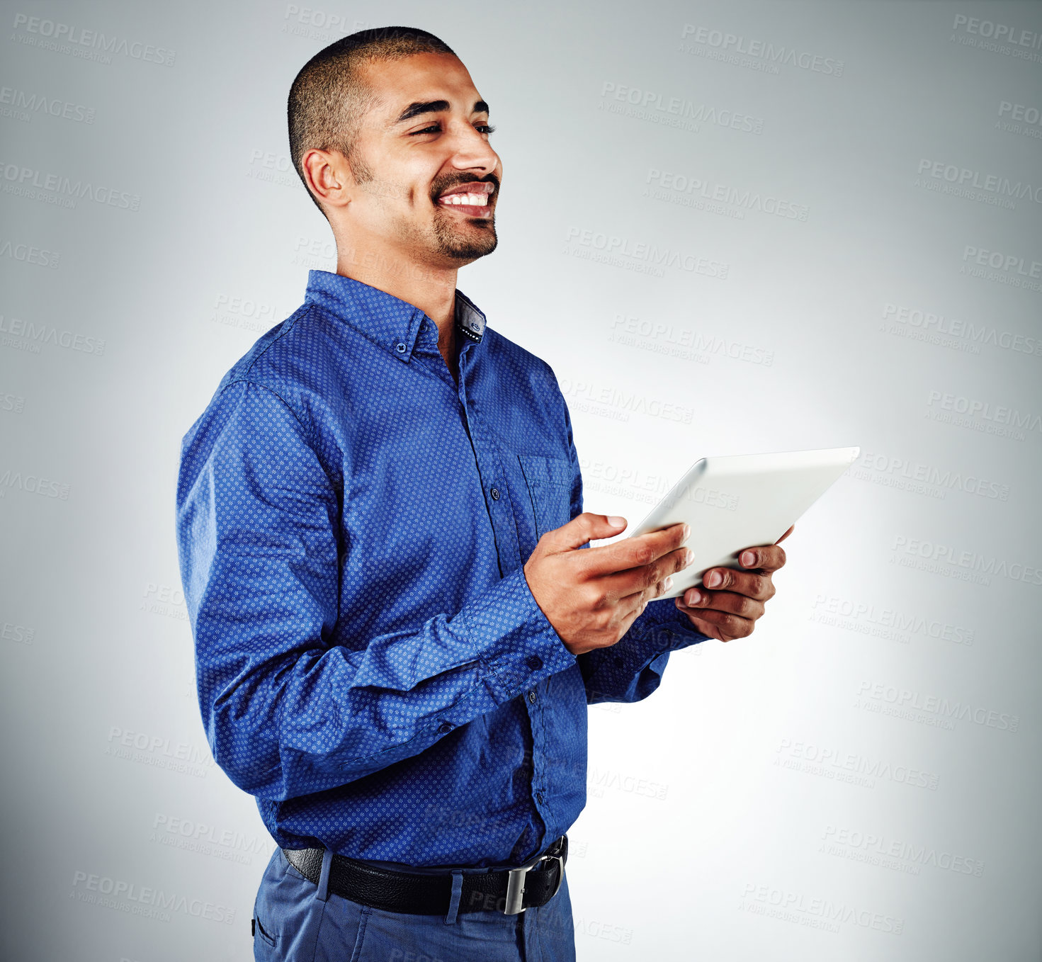 Buy stock photo Studio shot of a young businessman using his tablet against a grey background