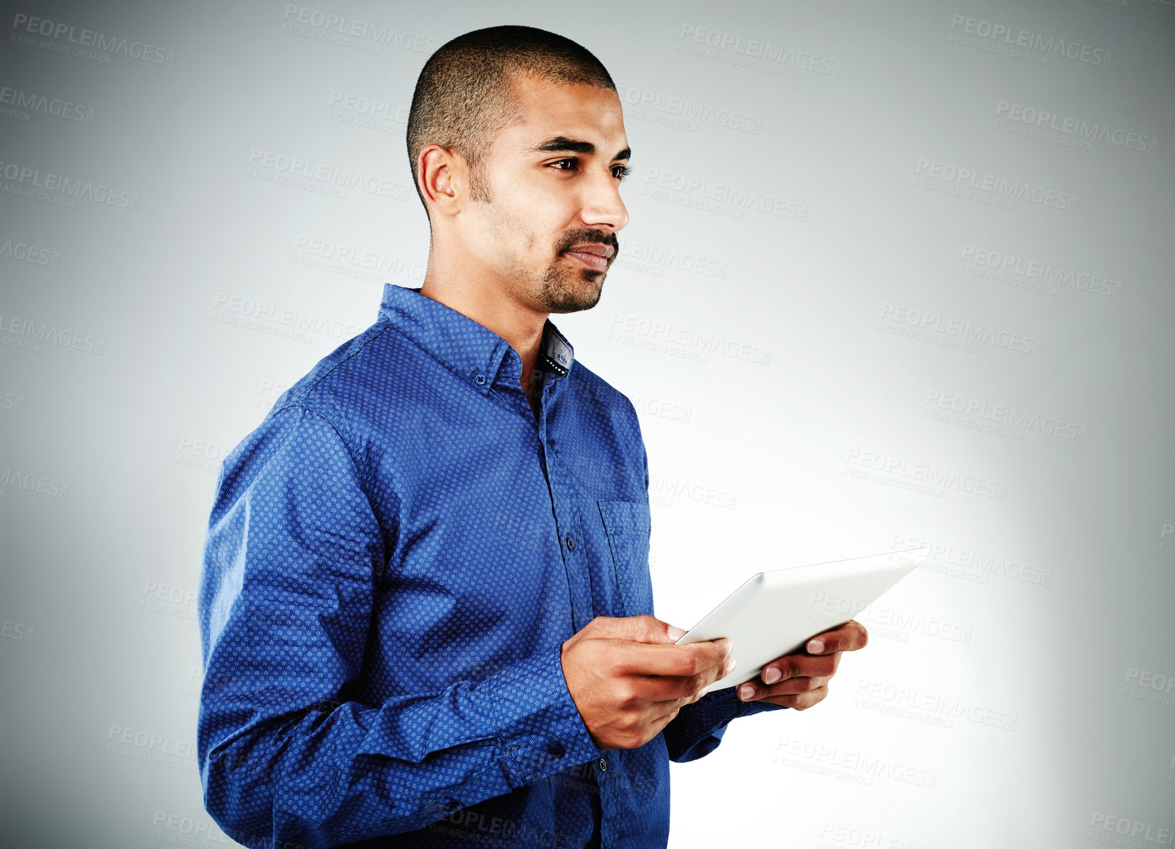 Buy stock photo Studio shot of a young businessman using his tablet against a grey background