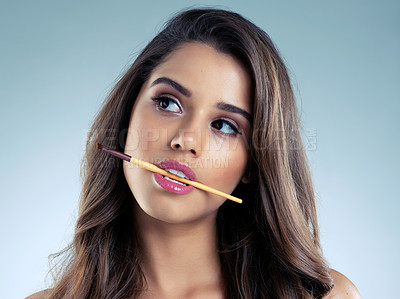 Buy stock photo Studio shot of a beautiful young woman posing with a cosmetic brush in her mouth