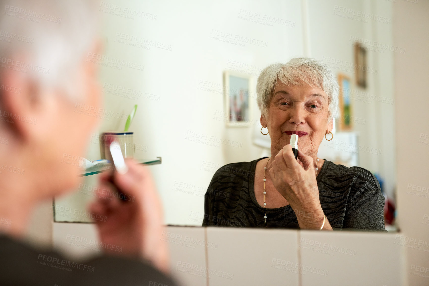 Buy stock photo Portrait of a happy senior woman applying makeup while looking in the mirror