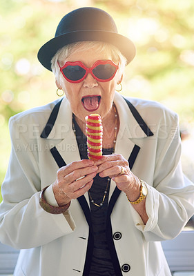 Buy stock photo Portrait of a fun-loving senior woman eating an ice-cream outside