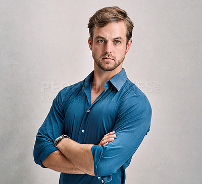 Buy stock photo Studio portrait of a handsome young man standing with his arms crossed