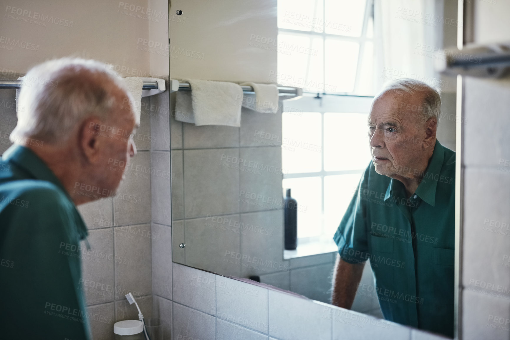 Buy stock photo Shot of a senior man looking in his bathroom mirror