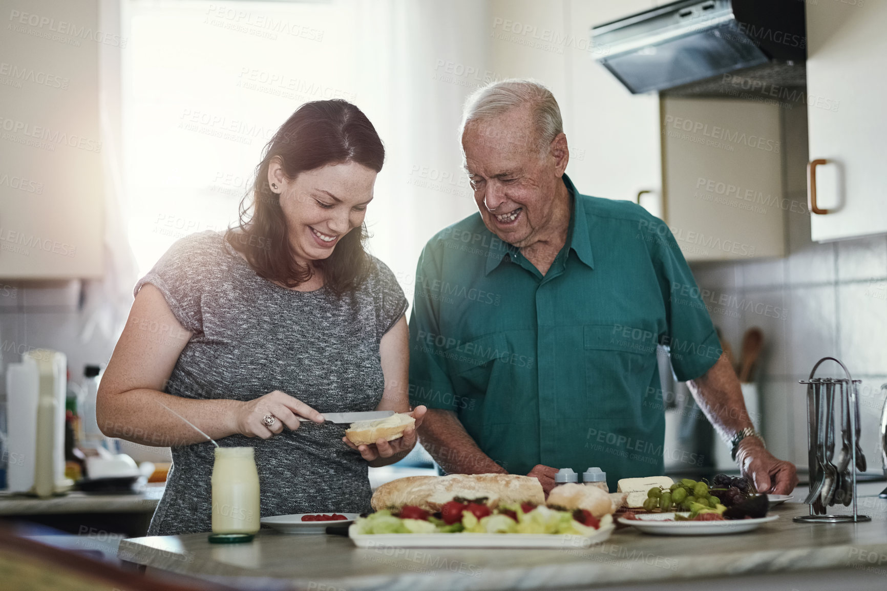 Buy stock photo Shot of a woman making her senior parent a sandwich