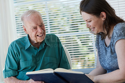 Buy stock photo Shot of a senior man and his daughter looking at a photo album together