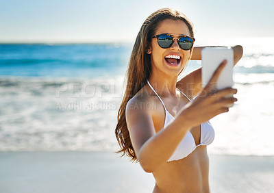 Buy stock photo Shot of a beautiful young woman taking a selfie at the beach