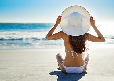 Buy stock photo Rearview shot of a young woman admiring the view while sitting on the beach
