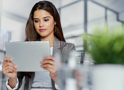 Buy stock photo Shot of a young businesswoman working on a digital tablet in an office