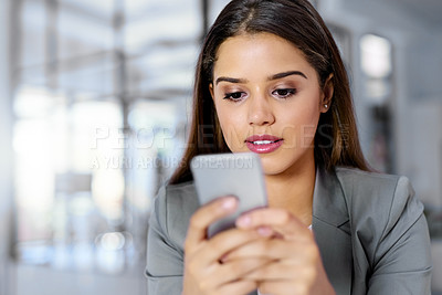 Buy stock photo Shot of a young businesswoman texting on a cellphone in an office