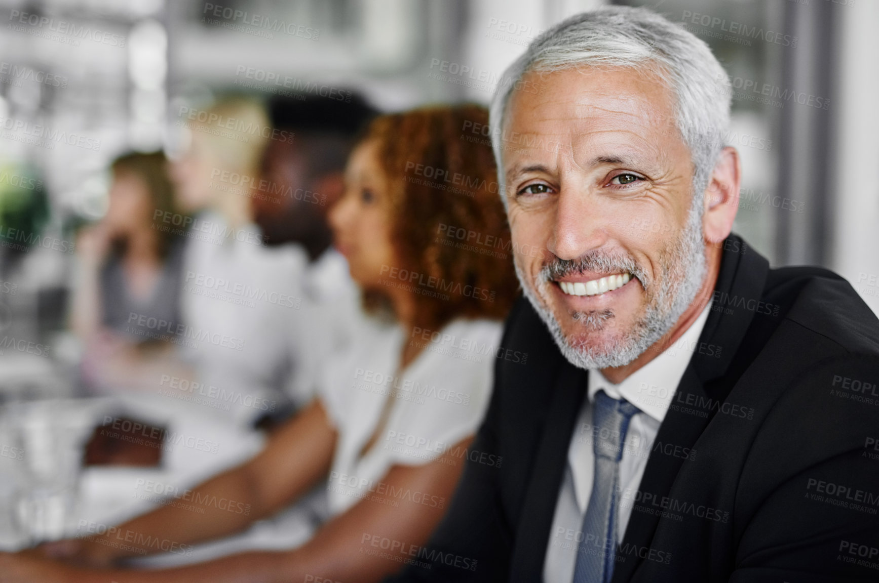 Buy stock photo Portrait of a businessman sitting in a boardroom meeting with colleagues blurred in the background