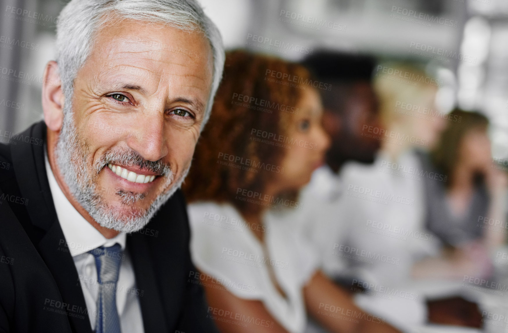 Buy stock photo Portrait of a businessman sitting in a boardroom meeting with colleagues blurred in the background