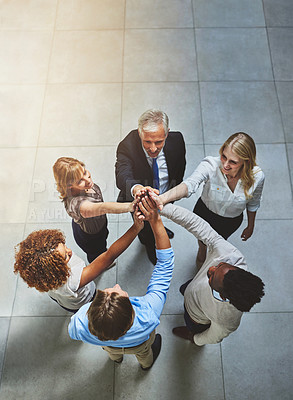 Buy stock photo High angle shot of a group of colleagues giving each other a high five in solidarity
