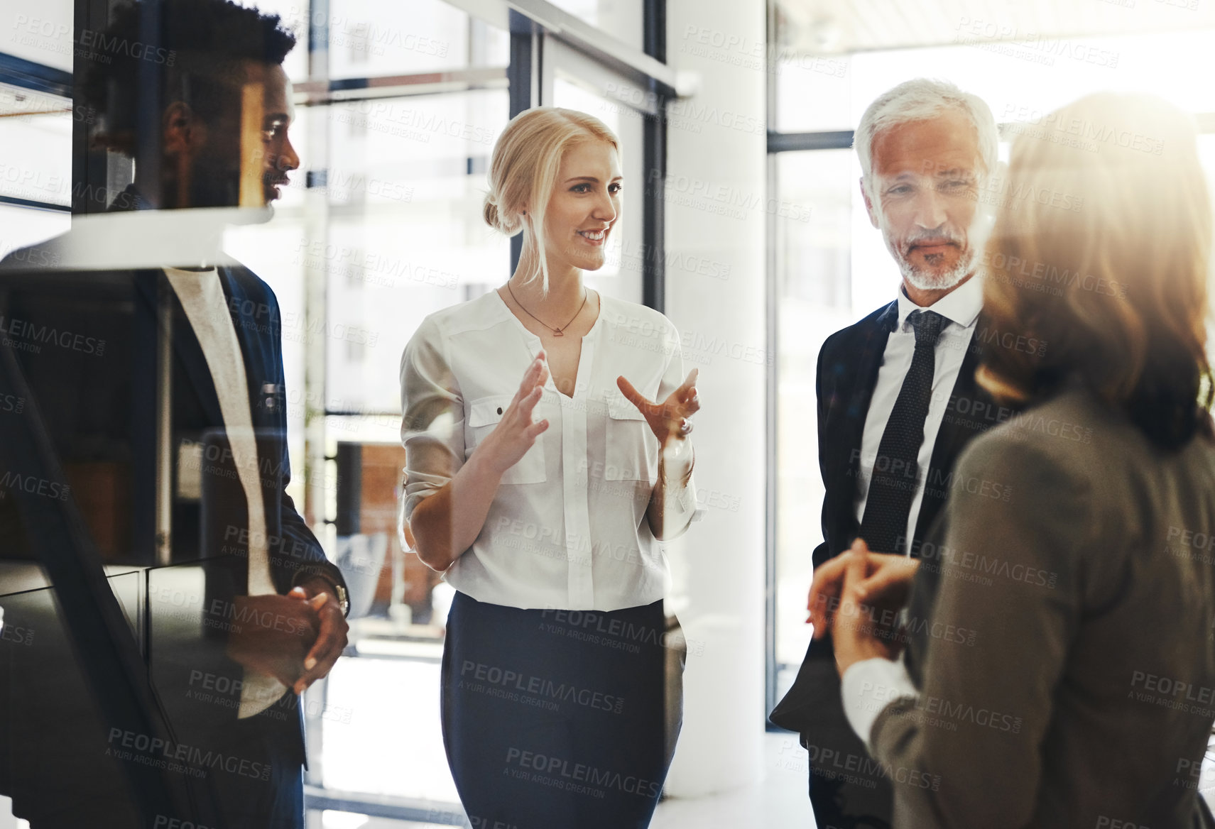 Buy stock photo Cropped shot of four businesspeople talking while standing in the office