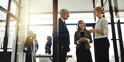 Buy stock photo Cropped shot of three businesspeople talking while standing in the office