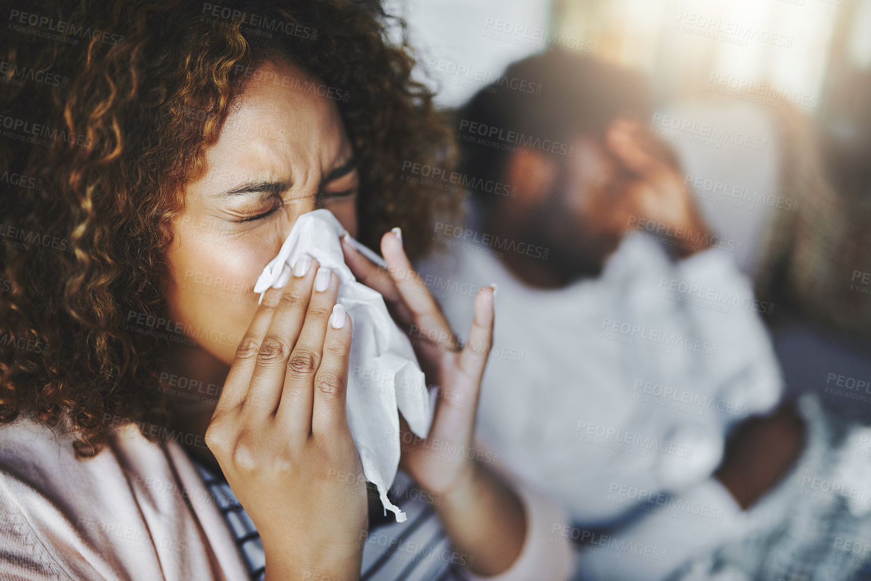 Buy stock photo Ill or sick woman with allergy, sinus infection sneezing in tissue or blowing nose during flu season at home. Sick girl caught a bad cold showing symptoms of covid, or suffering from a virus disease