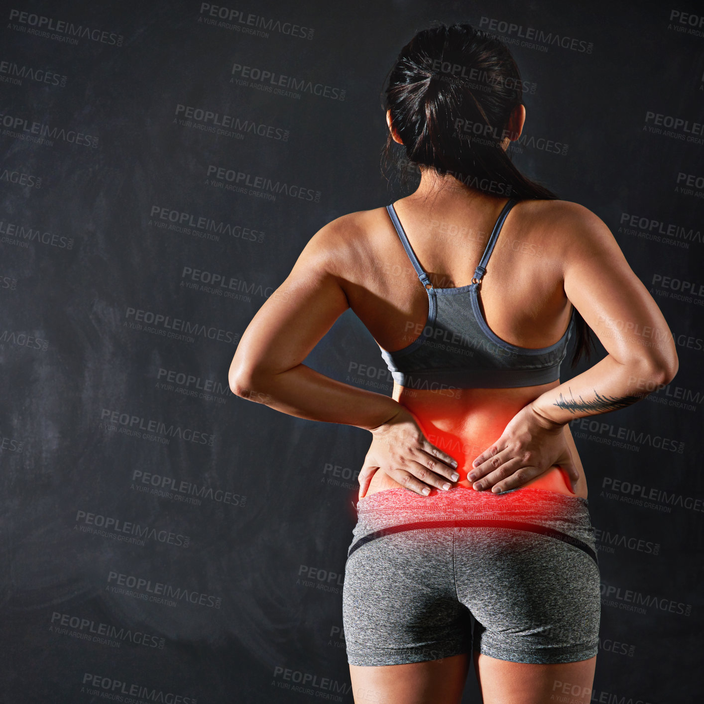 Buy stock photo Rearview shot of an unidentifiable sportswoman holding her back after injuring it